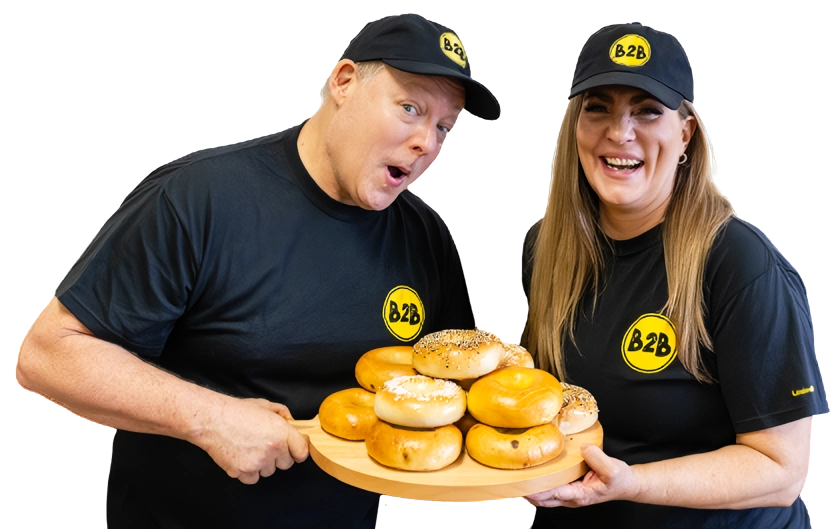A man and woman holding a tray of donuts.